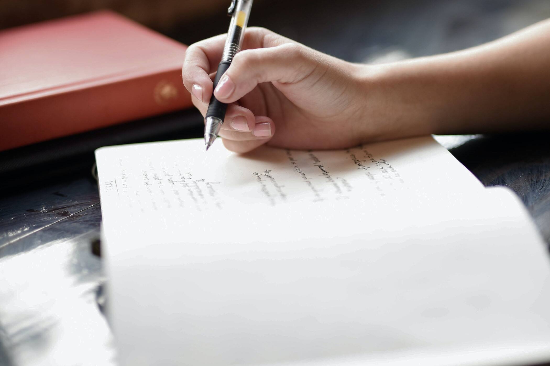 Person holding black pen ready to write on a page of a notebook