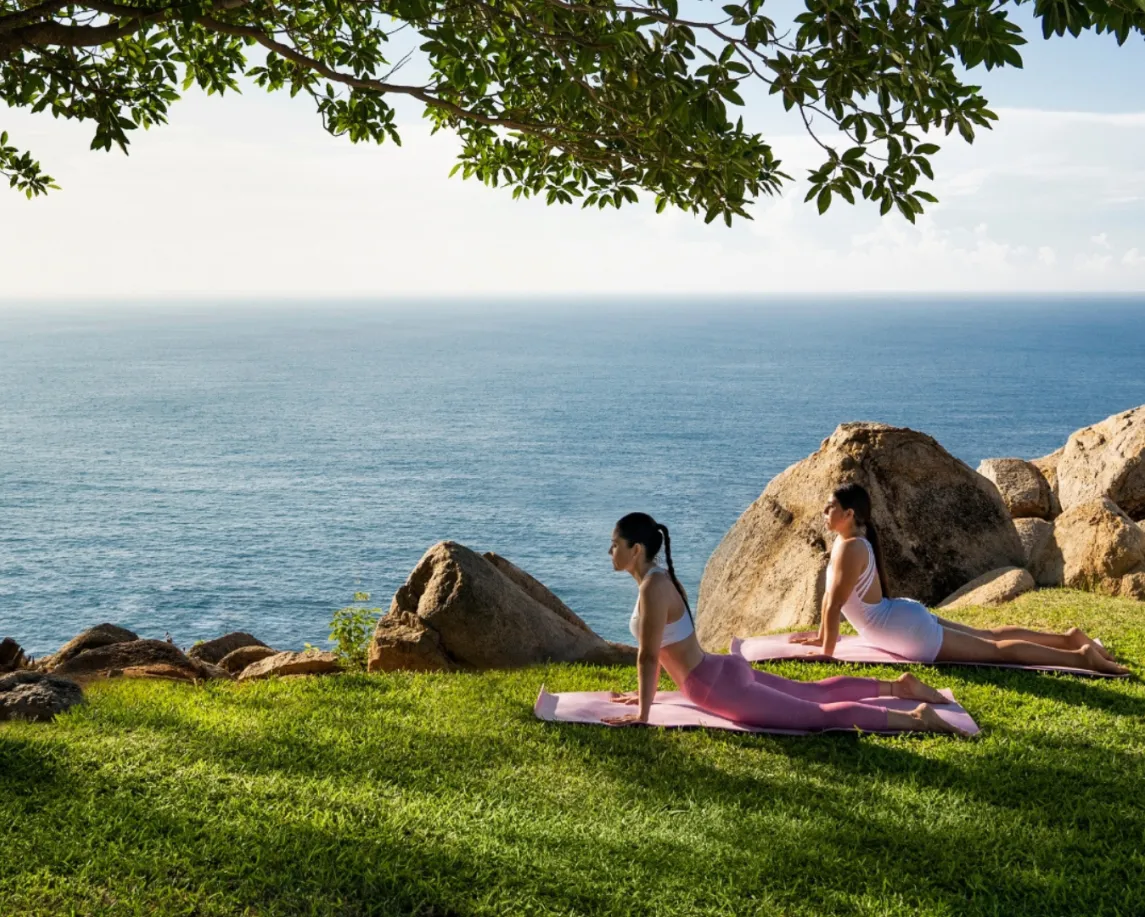 Two woman enjoying a morning session of yoga, surrounded by nature.