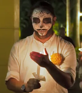 A person with face paint holding a candle for Hanal Pixán, Yucatan’s Day of the Dead in Mexico