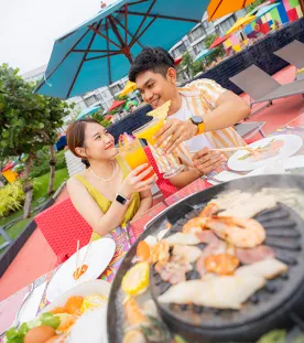 A person and person sitting at a table with food and a grill in Phuket, Thailand