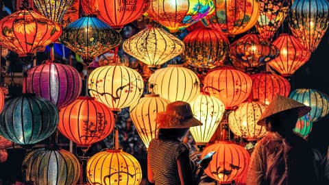 Two women standing beside a wall of lanterns
