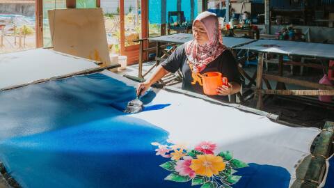 A woman carefully painting Batik in Angsana Teluk Bahang Penang