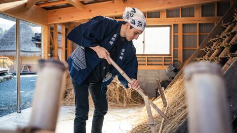 A man weaving suzuki grass for a roof as part of the Stay for Good experience at Dhawa Yura Kyoto